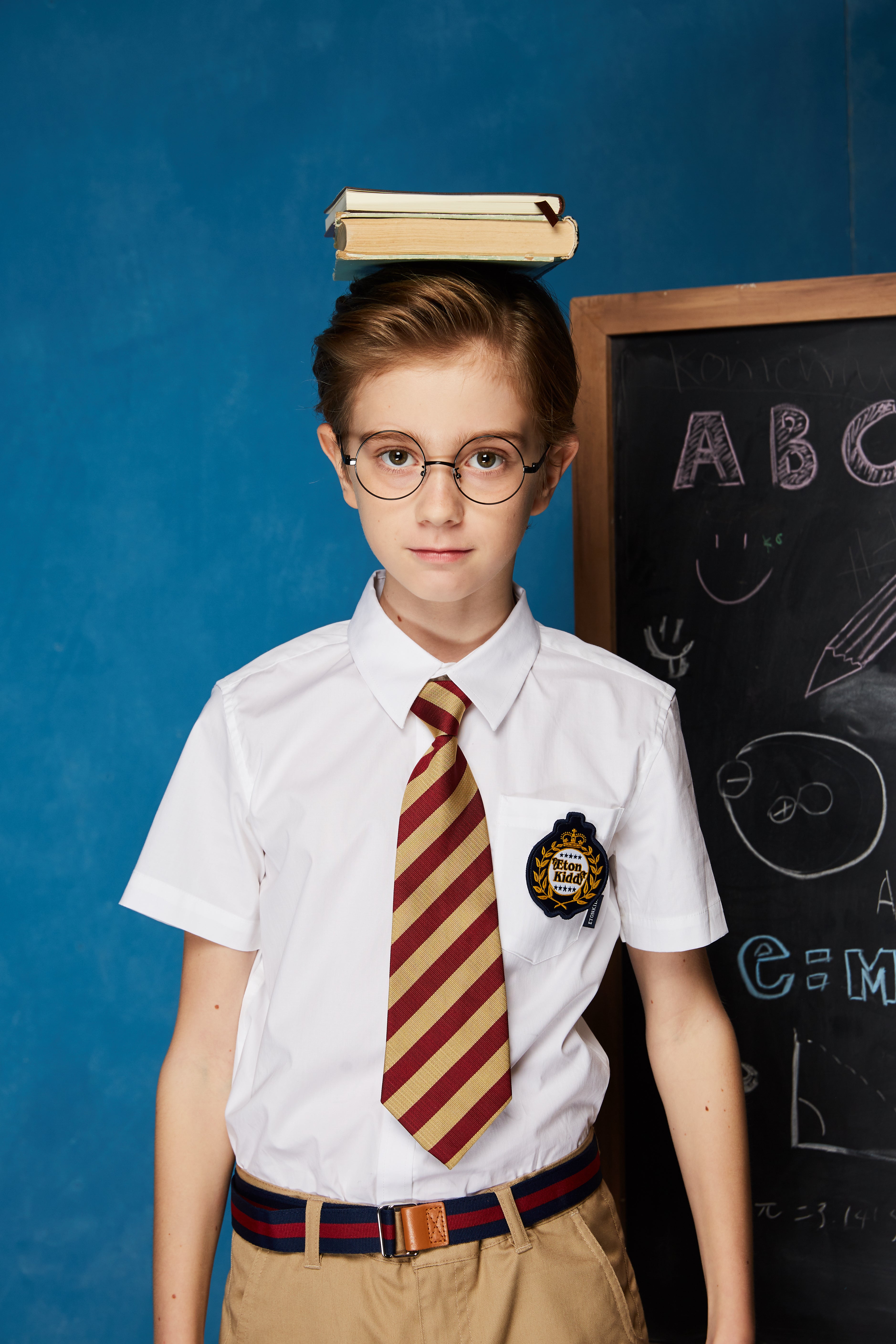 Boy wearing a white short-sleeve summer button-up shirt with front pocket by Everanne, casual boys' tops for warm weather.