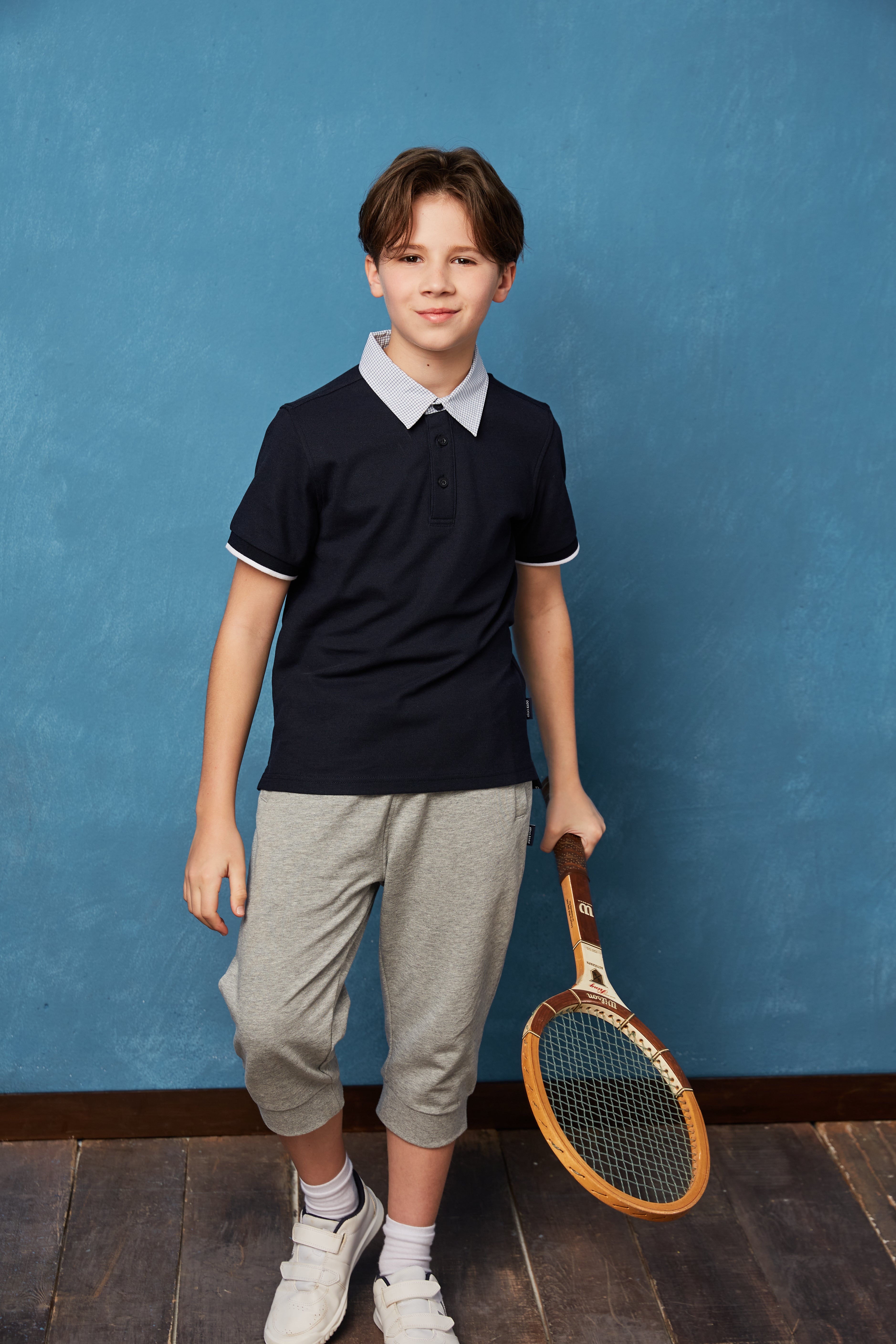 Unisex kids navy polo shirt by Everanne, short sleeve pique mesh cotton blend T-shirt displayed on a child.