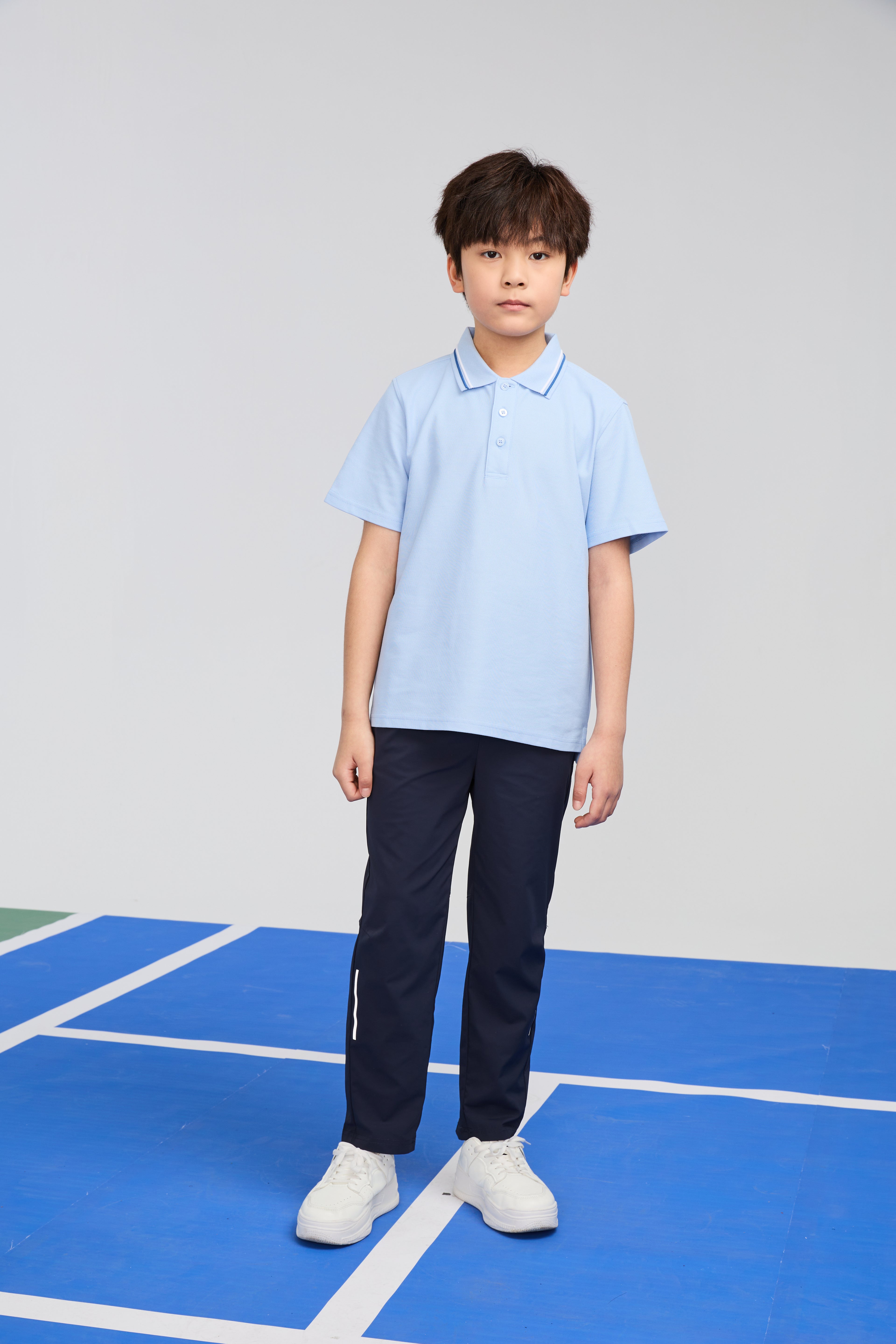 Light blue Everanne unisex kids polo shirt with short sleeves and cotton blend piqué mesh fabric, laid flat on white background.
